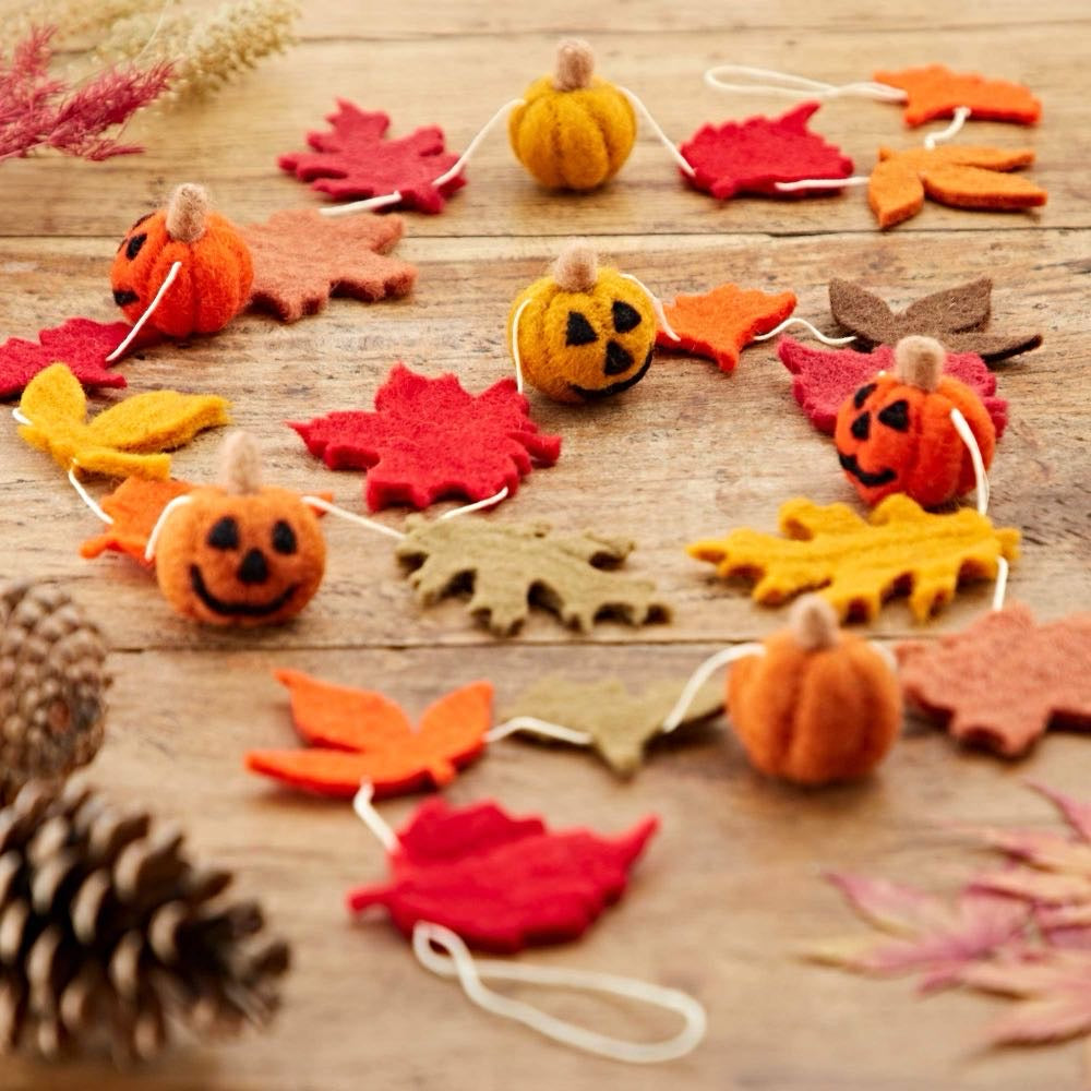 Felt autumn garland with orange and yellow pumpkins and red, orange and brown leaves on a wooden table