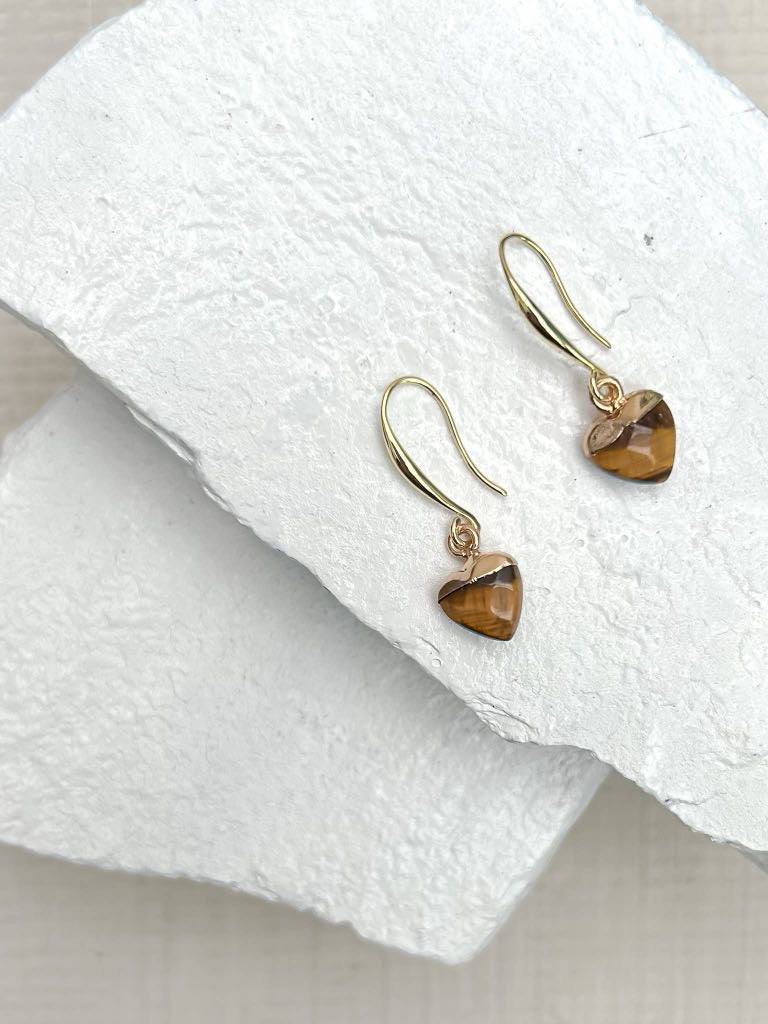 Tiger's eye heart drop earrings on gold plated hooks resting on white stone