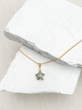 Green aventurine star pendant necklace on fine gold plated chain resting on white stone