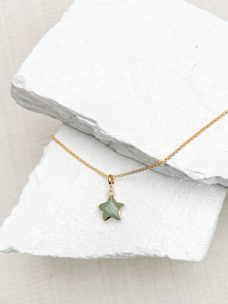 Green aventurine star pendant necklace on fine gold plated chain resting on white stone