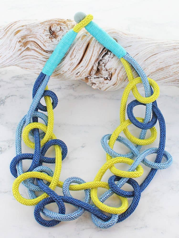 Chunky cord link statement necklace in cobalt blue, light blue and lime on a display bust