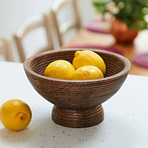 A large mango wood toned hand-turned wooden bowl with beautiful concentric ridged rings covering the inside and outside, featuring a wide mouth and slightly raised footed base.