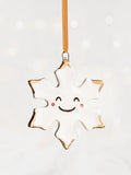 White Snowflake Ceramic Christmas Ornament with a smiley face and Gold Tips