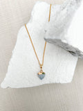 Blue aventurine heart pendant necklace on fine gold plated chain resting on white stone