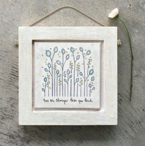 Small square East of India distressed whitewashed wooden framed picture featuring a delicate wildflower illustration with blue-grey poppy-style flower heads and small gold dot details on a white background, with the sentiment "You are stronger than you think," hung with natural jute twine.