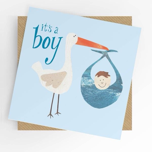 Square new baby boy greeting card with a soft blue background featuring a collage-style illustration of a stork carrying a baby boy in a blue bundle, with teal script reading "it's a boy," shown alongside a kraft brown envelope.