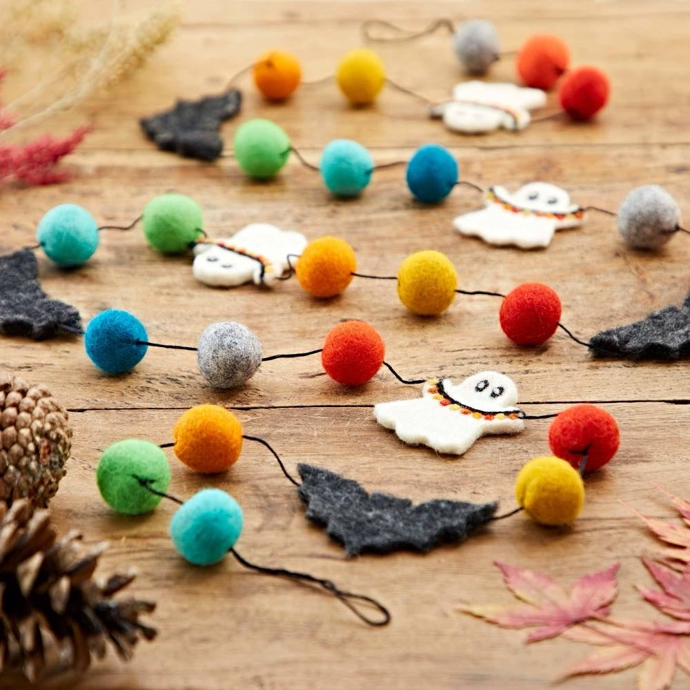  Felt Halloween garland with colourful pom poms, white ghosts and black bats on a wooden table