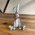 Rustic resin sitting bunny decoration in grey with twine bow—perfect for shelves, mantels and Easter displays. A cute Easter bunny ornament and gift idea.