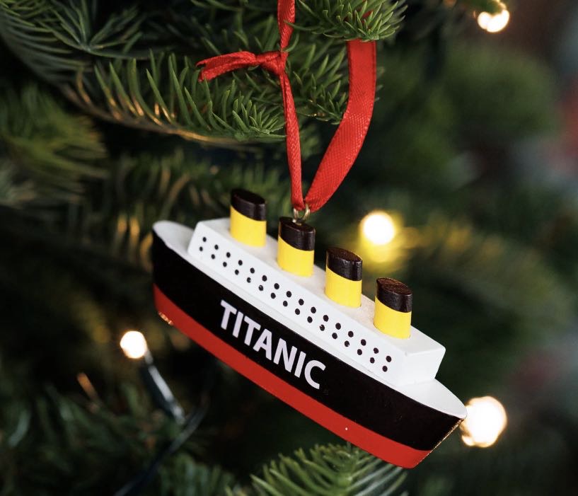 Hand painted wooden Titanic ship Christmas decoration with red ribbon hanging on a Christmas tree