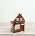 Red ceramic Christmas house tealight holder with snowy roof, green garland, wreath door and Christmas tree