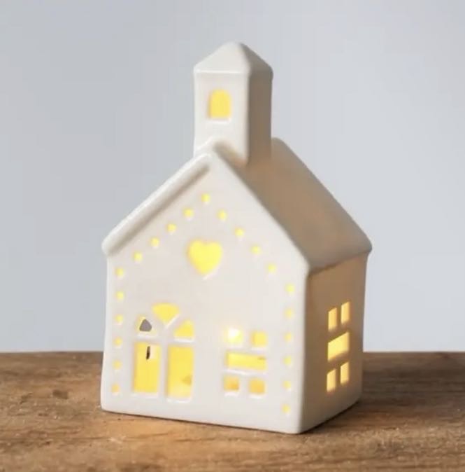 White ceramic light up church with bell tower, heart cut-out and glowing windows on a wooden shelf