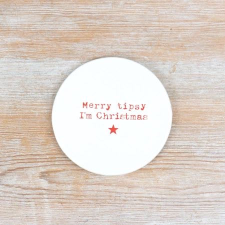 Round white ceramic coaster with the words Merry tipsy I'm Christmas in red lettering and a red star