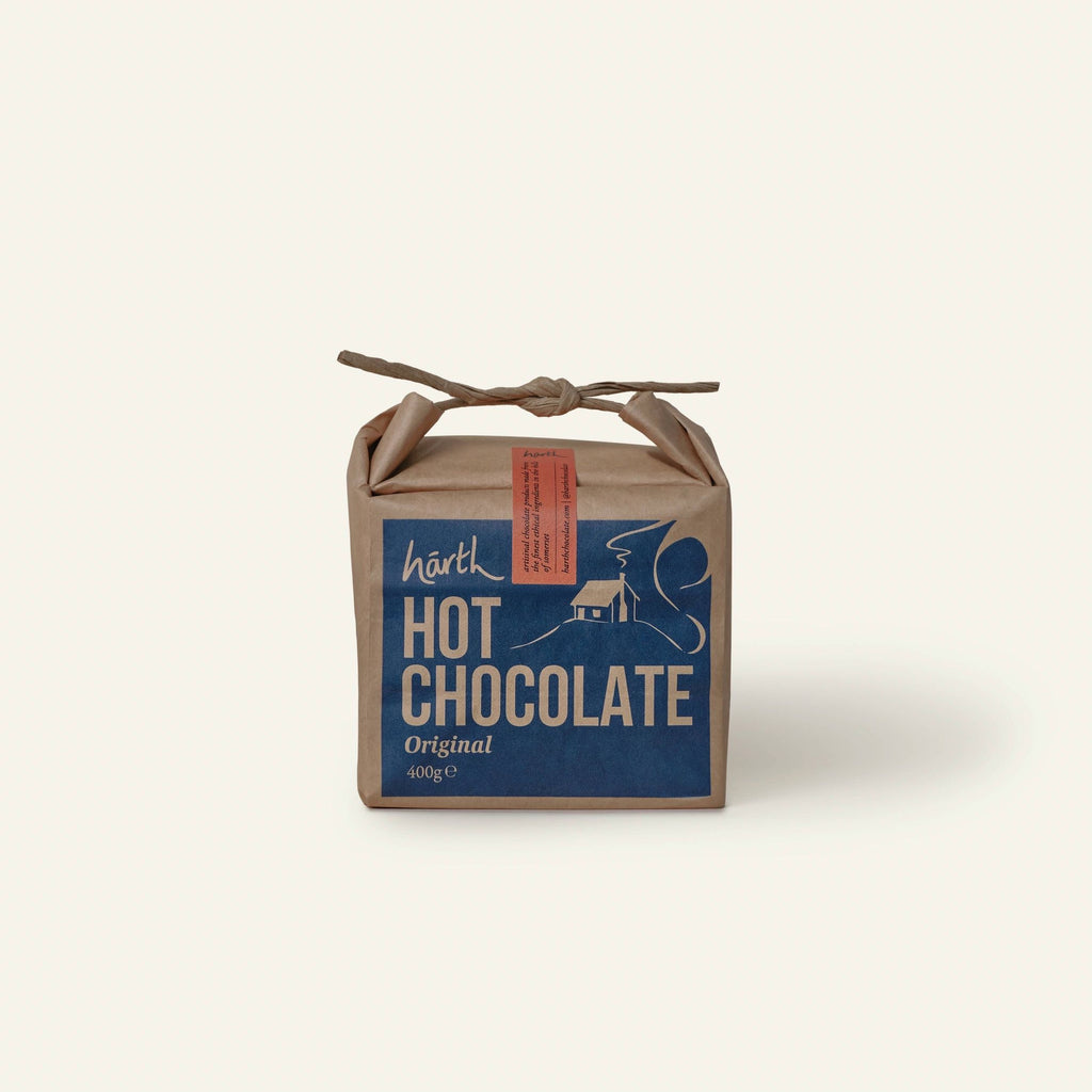 Harth Original Hot Chocolate 400g in brown paper packaging hanging on a silver birch tree