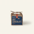 Harth Original Hot Chocolate 400g in brown paper packaging hanging on a silver birch tree